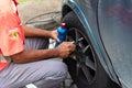 Salvador, Bahia, Brazil - August 11, 2023: A gas station worker is seen pumping up a car tire on Avenida Tancredo Neves