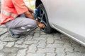 Salvador, Bahia, Brazil - August 11, 2023: A gas station worker is seen pumping up a car tire on Avenida Tancredo Neves