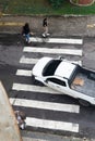 Salvador, Bahia, Brazil - August 11, 2023: View from above of a car and pedestrians crossing the lane on one of the streets next