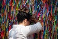 A Catholic woman praying against the wall of colorful ribbons at Senhor do Bonfim church