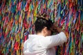 A Catholic woman praying against the wall of colorful ribbons at Senhor do Bonfim church
