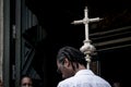 Man entering the catholic church holding the silver cross