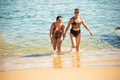 Salvador, Bahia, Brazil - June 04, 2022: Mother and daughter, in bikinis, are coming out of the water at Porto da Barra beach in