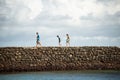 People walk on the stone breakwater of beach Royalty Free Stock Photo