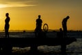 Silhouette of young people jumping from the Crush bridge at the yellow sunset on Ribeira beach in Salvador (BA Royalty Free Stock Photo