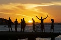 Silhouette of young people jumping from the Crush bridge at the yellow sunset on Ribeira beach in Salvador (BA Royalty Free Stock Photo