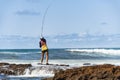 Fisherman woman with fishing rod on the rocks fishing