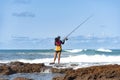 Fisherman woman with fishing rod on the rocks fishing