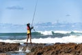 Fisherman woman with fishing rod on the rocks fishing