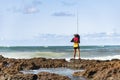 Fisherman woman with fishing rod on the rocks fishing