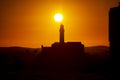Silhouette of a lighthouse against a beautiful and dramatic orange sunset