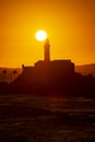 Silhouette of a lighthouse against a beautiful and dramatic orange sunset