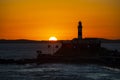 Silhouette of a lighthouse against a beautiful and dramatic orange sunset