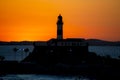 Silhouette of a lighthouse against a beautiful and dramatic orange sunset