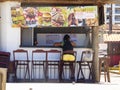 Woman sitting on a stool of a snack bar selling typical Brazilian snacks by the beach
