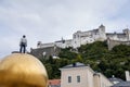 Salzburg, Austria, 28 August 2021: Man on Goldene Kugel statue, sculpture Sphaera, old medieval castle Festung Hohensalzburg,