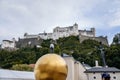 Salzburg, Austria, 28 August 2021: Man on Goldene Kugel statue, sculpture Sphaera, old medieval castle Festung Hohensalzburg,