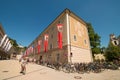 Girl riding a bicycle along bike parking near University building and Salzburg festival flags in the old town of Salzburg, Austria