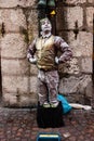 Salzburg, Austria, 01.11.2013. A living statue of a street performer covered in silver paint depicts a dwarf harlequin