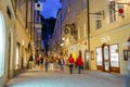 Street scene, people walking along narrow road between tall trad