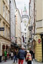 Street scene, people walking along narrow raod between tall trad