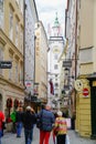 Typical old town European city street with up-market shops and tourists with church clock tower at end Royalty Free Stock Photo