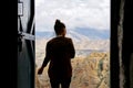 A Nepalese woman stands against the background of the doorway and looks at the Himalayan mountains.