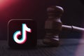 SAMARA, Russia - March 14, 2023: The judge's hammer on the background of the logo of the TikTok social network. The