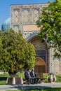 SAMARKAND, UZBEKISTAN: APRIL 27, 2018: Local men sitting on a bench in front of Bibi-Khanym Mosque in Samarkand