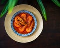 `Sambal Udang` or Spicy Chili prawns in a blue and wooden plate over wooden background. South East Asian cuisine. Royalty Free Stock Photo