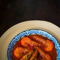 `Sambal Udang` or Spicy Chili prawns in a blue and wooden plate over wooden background. South East Asian cuisine. Royalty Free Stock Photo