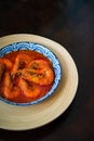 `Sambal Udang` or Spicy Chili prawns in a blue and wooden plate over wooden background. South East Asian cuisine. Royalty Free Stock Photo