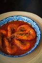 `Sambal Udang` or Spicy Chili prawns in a blue and wooden plate over wooden background. South East Asian cuisine. Royalty Free Stock Photo