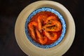 `Sambal Udang` or Spicy Chili prawns in a blue and wooden plate over wooden background. South East Asian cuisine. Royalty Free Stock Photo