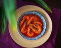 `Sambal Udang` or Spicy Chili prawns in a blue and wooden plate over wooden background. South East Asian cuisine. Royalty Free Stock Photo