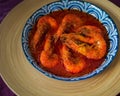 `Sambal Udang` or Spicy Chili prawns in a blue and wooden plate over wooden background. South East Asian cuisine. Royalty Free Stock Photo