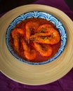 `Sambal Udang` or Spicy Chili prawns in a blue and wooden plate over wooden background. South East Asian cuisine. Royalty Free Stock Photo