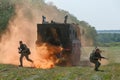 Several Russian special forces fighters getting out from an armored car in the orange screening smoke