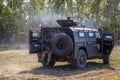 Soldiers of special purpose detachment driving in an armoured car across the field and shooting a machine gun