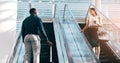 Same goal, different paths. two young businesspeople greeting while passing each other on the escalators in a modern Royalty Free Stock Photo