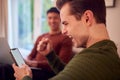 Same Sex Male Couple On Sofa At Home Using Mobile Phone And Laptop Watching Sports And Celebrating Royalty Free Stock Photo