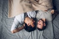 Handsome sleepy man with bristle kissing good night male partner lying in bed Royalty Free Stock Photo