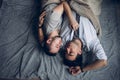 Handsome sleepy man with bristle kissing good night male partner lying in bed