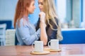 Same-sex relationships. Happy lesbian couple sitting in a cafe. Girls gently hold hands and drink coffee. Embrace of Royalty Free Stock Photo