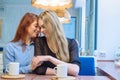 Same-sex relationships. Happy lesbian couple sitting in a cafe. Girls gently hold hands and drink coffee. Embrace of Royalty Free Stock Photo