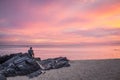 The Samila beach in Songkhla Province at sunrise with people sitting on a rock