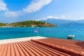 Orange tile roof of a house with Greek flag waving against blue sea background on coast of Samos island, Greece Royalty Free Stock Photo