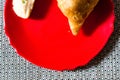 Samosa, peda barfi on red plate and woven mat, typical indian snack breakfast