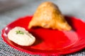 Samosa, peda barfi on red plate and woven mat, typical indian snack breakfast