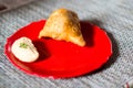 Samosa, peda barfi on red plate and woven mat, typical indian snack breakfast